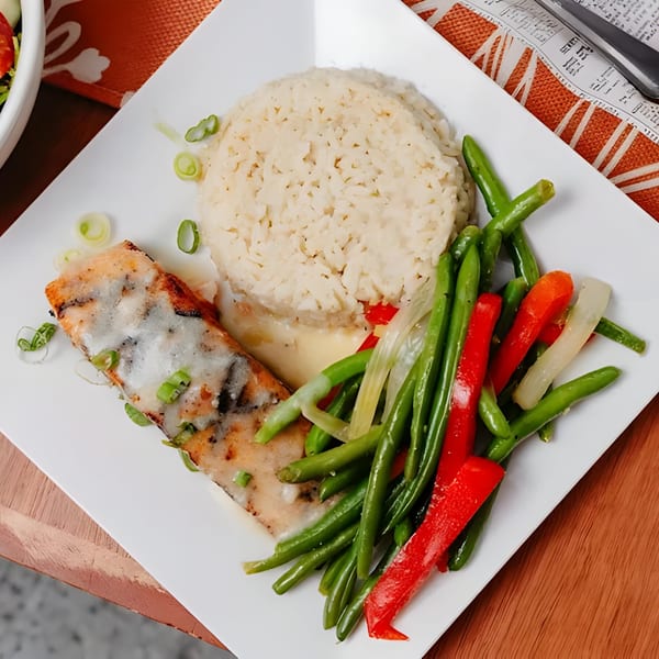 Grilled fish with rice, green beans, and red peppers on a white plate at Dox bar.